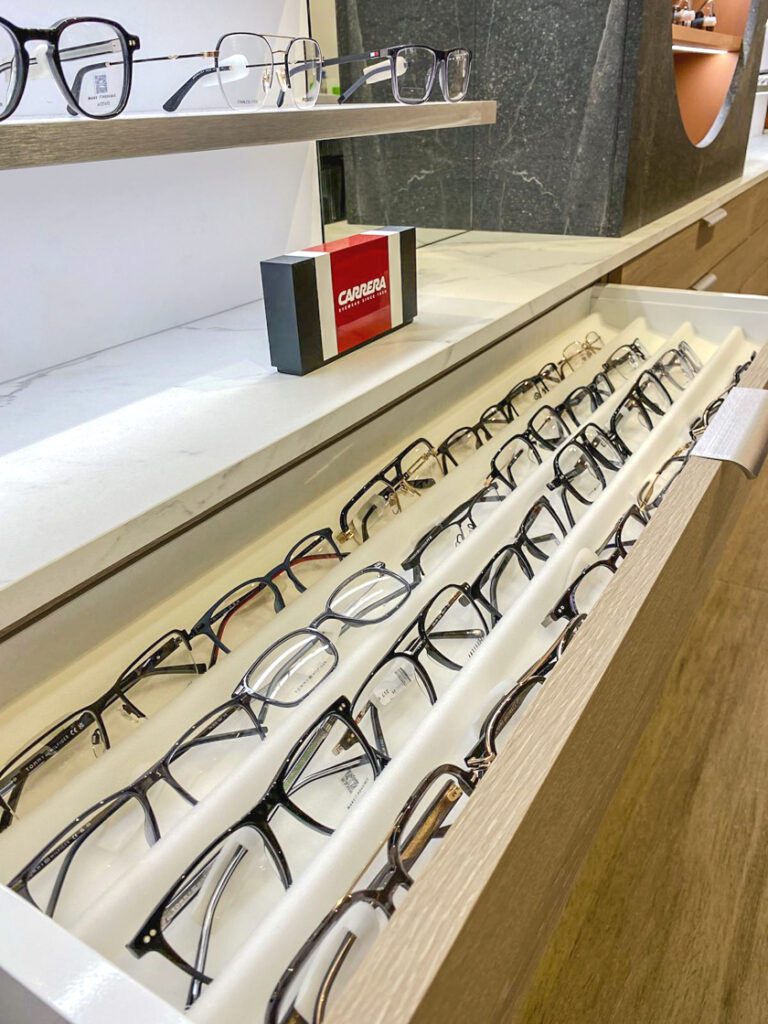 Tiroir de rangement pour lunettes dans un magasin d’optique avec compartiments organisés et présentation soignée de montures optiques.