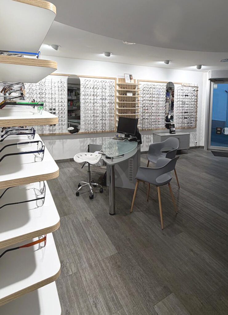 Agencement optique avec présentoir mural de lunettes, espace de vente ergonomique et circulation fluide dans un environnement moderne.