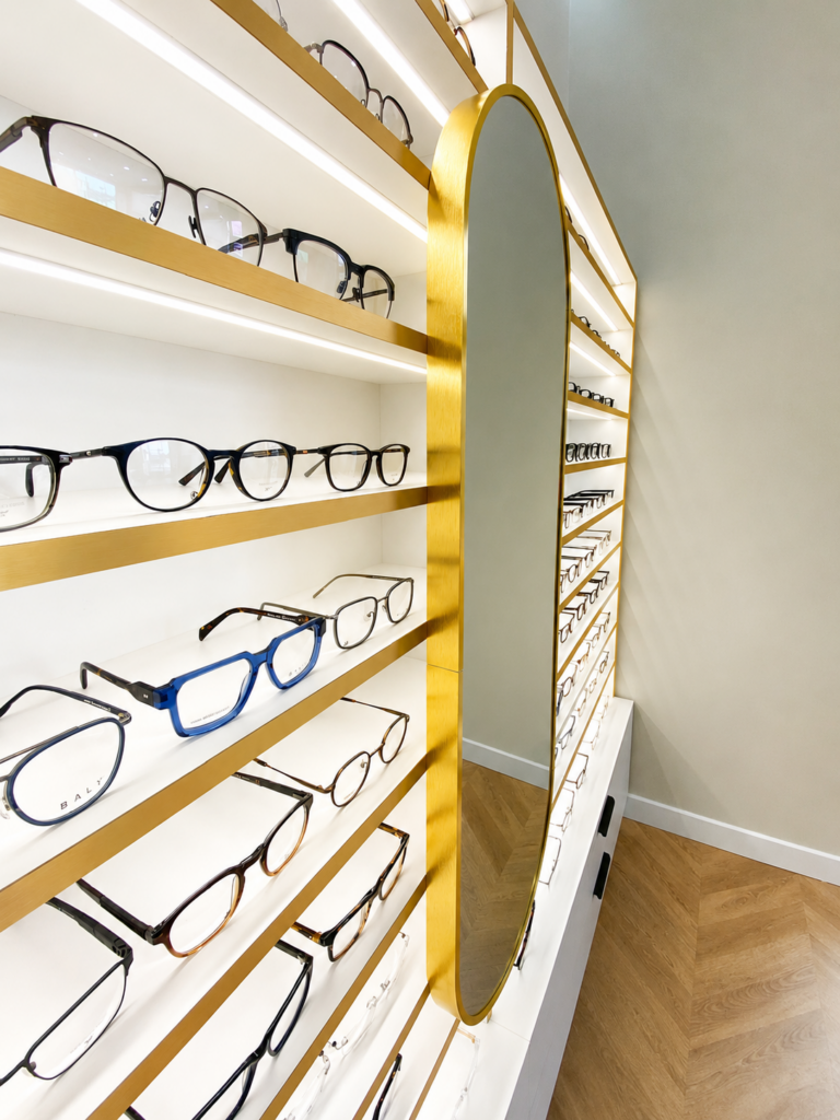 Miroir doré intégré dans un mobilier d’optique sur mesure avec présentation de montures chez Lookin’Optic à Deuil-la-Barre