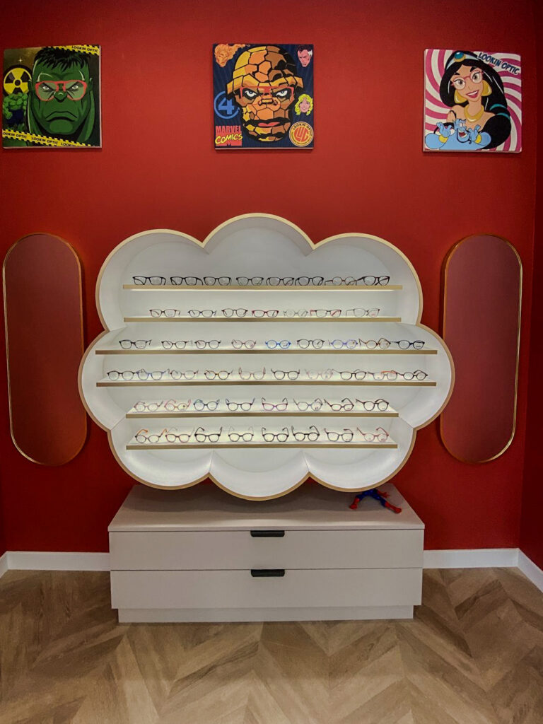 Espace enfant personnalisé avec mobilier en forme de nuage pour la présentation de lunettes chez Lookin’Optic