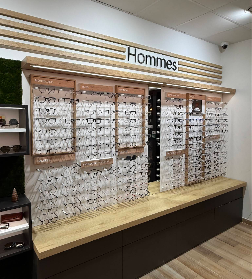 Mur de présentation homme avec mobilier sur mesure et mise en avant des collections de lunettes dans le magasin d'optique de Pélissanne.