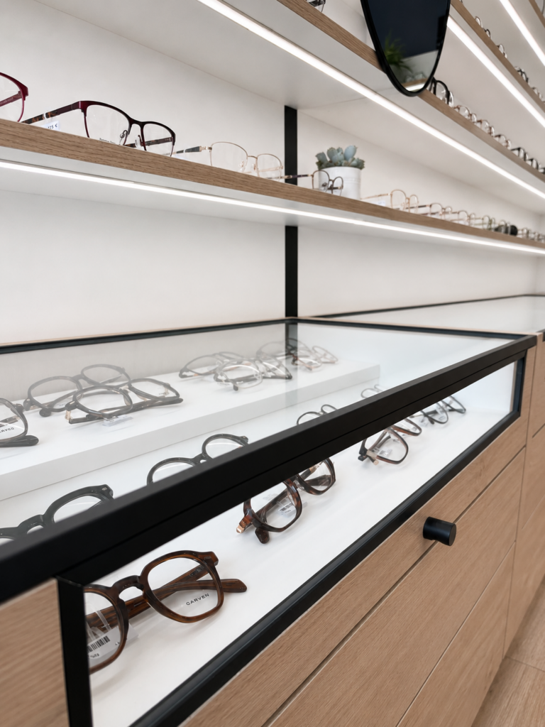 Vitrine de présentation de montures intégrée dans un mobilier bois et métal noir réalisé pour Optique Chabert à Nice.
